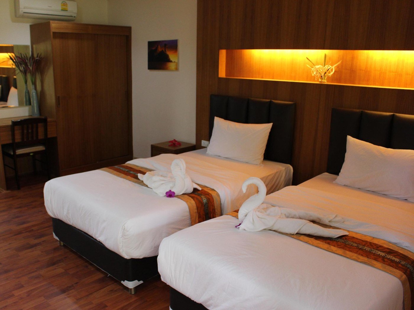 Twin bedroom with wooden wall panels and folded towels at Aonang Bunk Resort