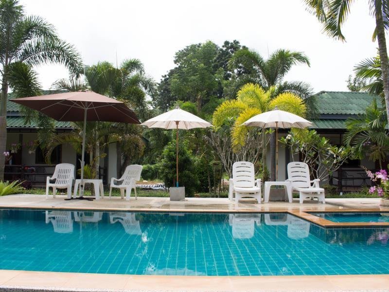 Outdoor swimming pool with loungers and umbrellas at Aonang Bunk Resort