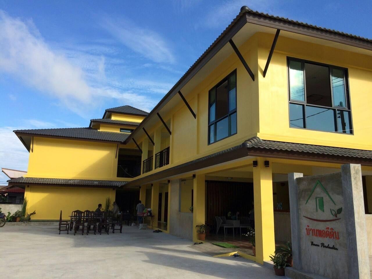 Yellow accommodation building and courtyard at Baan Pordeedin