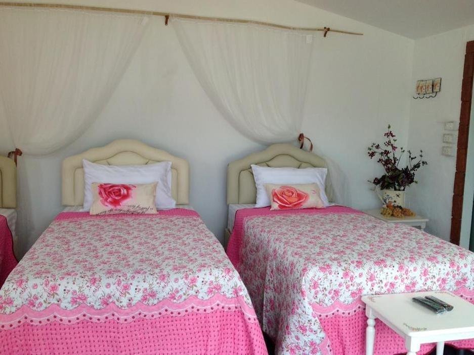 Twin beds with floral pink bedding and canopy netting at Flora Hill Pongyang Resort