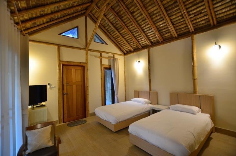 Twin bedroom beneath a pitched timber ceiling at Isaree Secret Garden