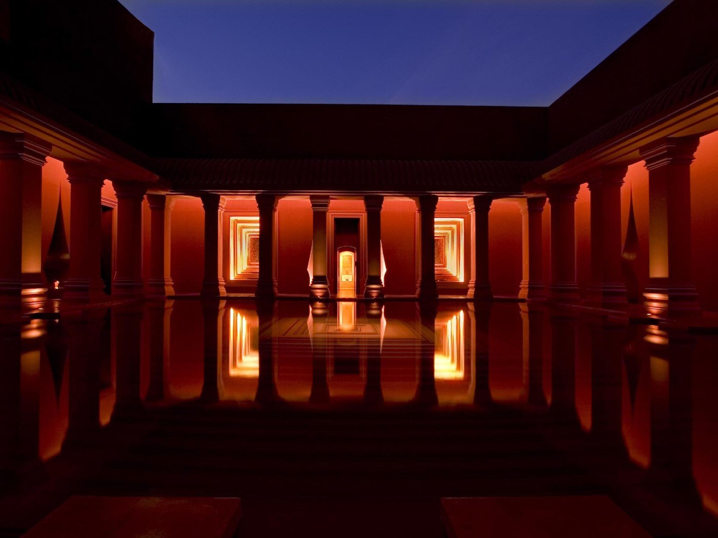 Illuminated courtyard and reflecting water at The Barai